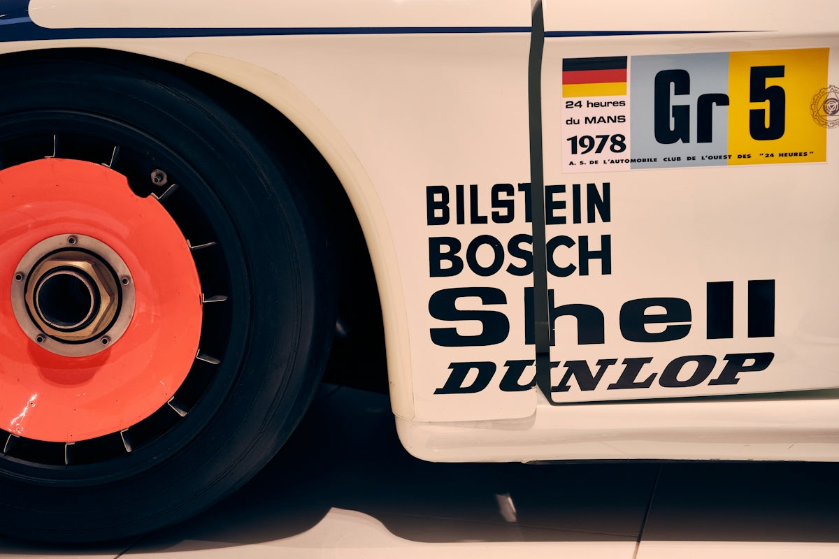 Vintage race car with sponsor logos and orange wheel